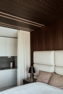 Modernt sovrum med en akustikpanel i valnöt som löper från golv upp i taket